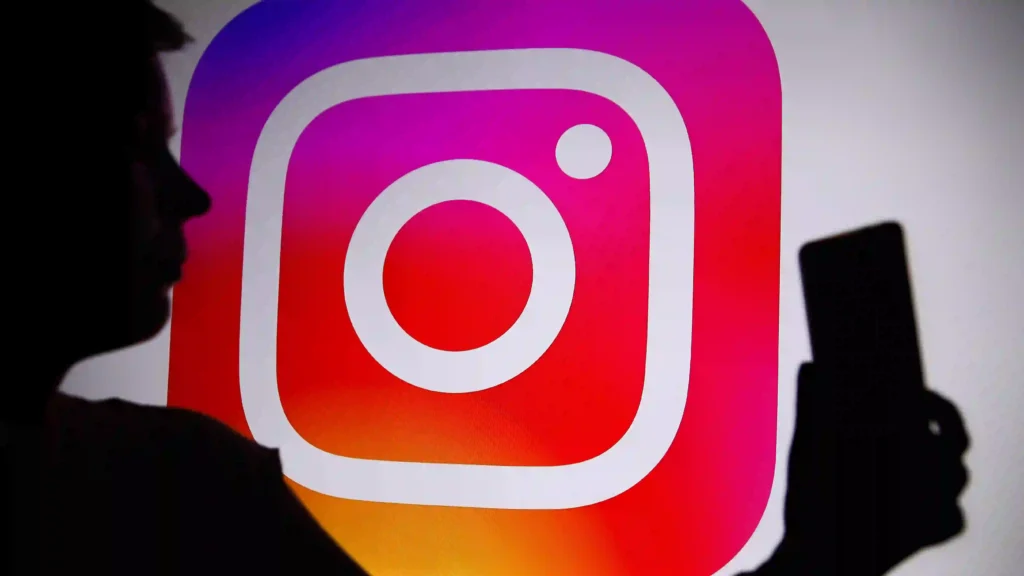 Instagram app logo background with a dark silhouette of a mobile phone user.